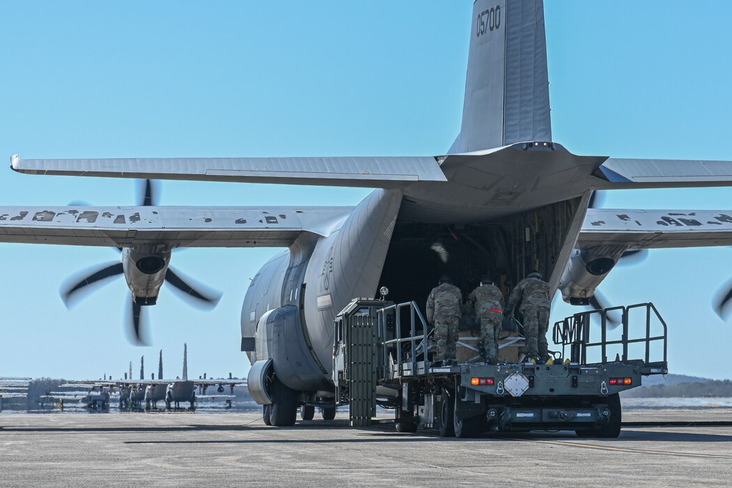 A C-130 is refueled and loaded with cargo on the flightline, while the engines run.