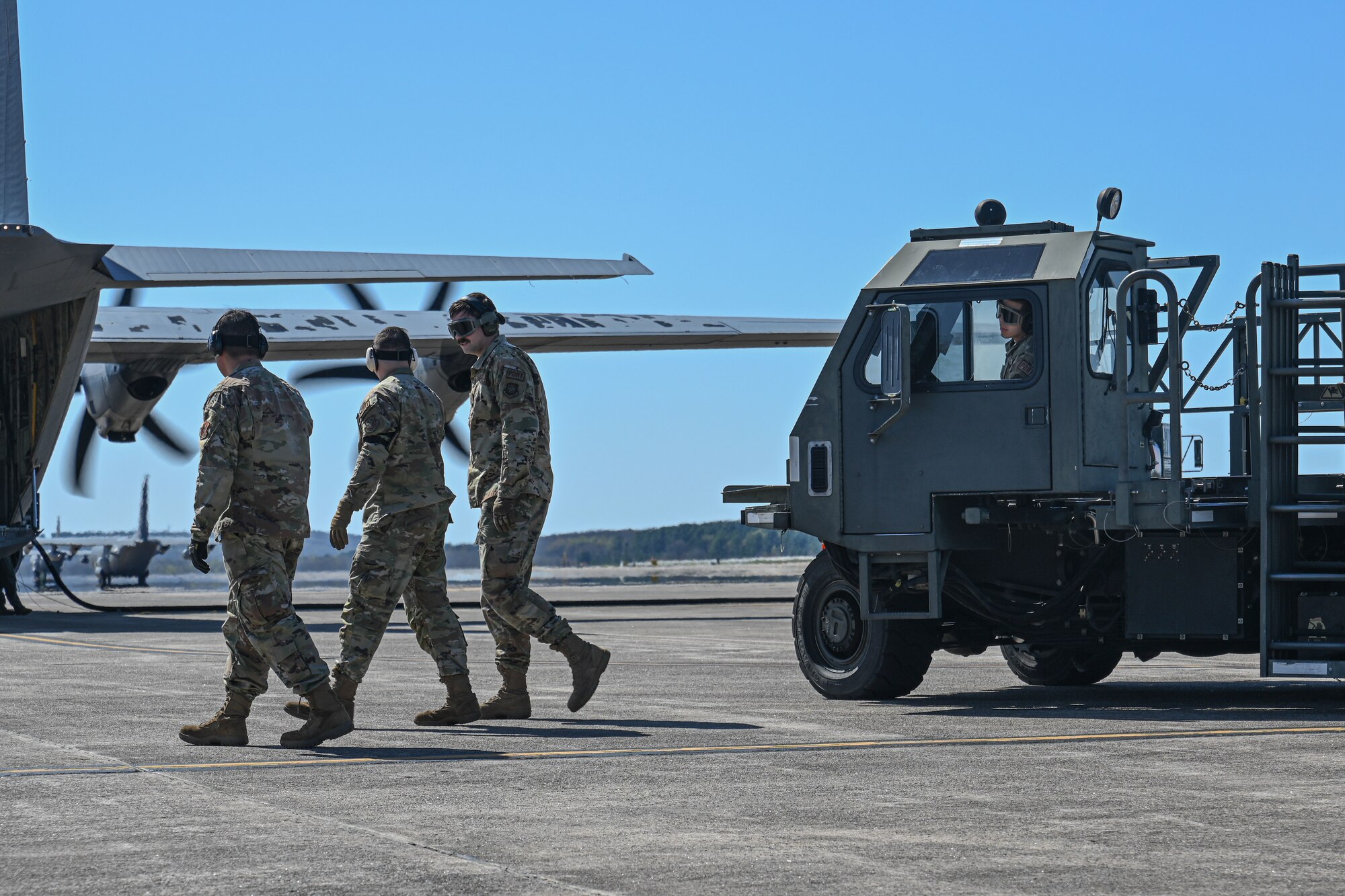 A C-130 is refueled and loaded with cargo on the flightline, while the engines run.