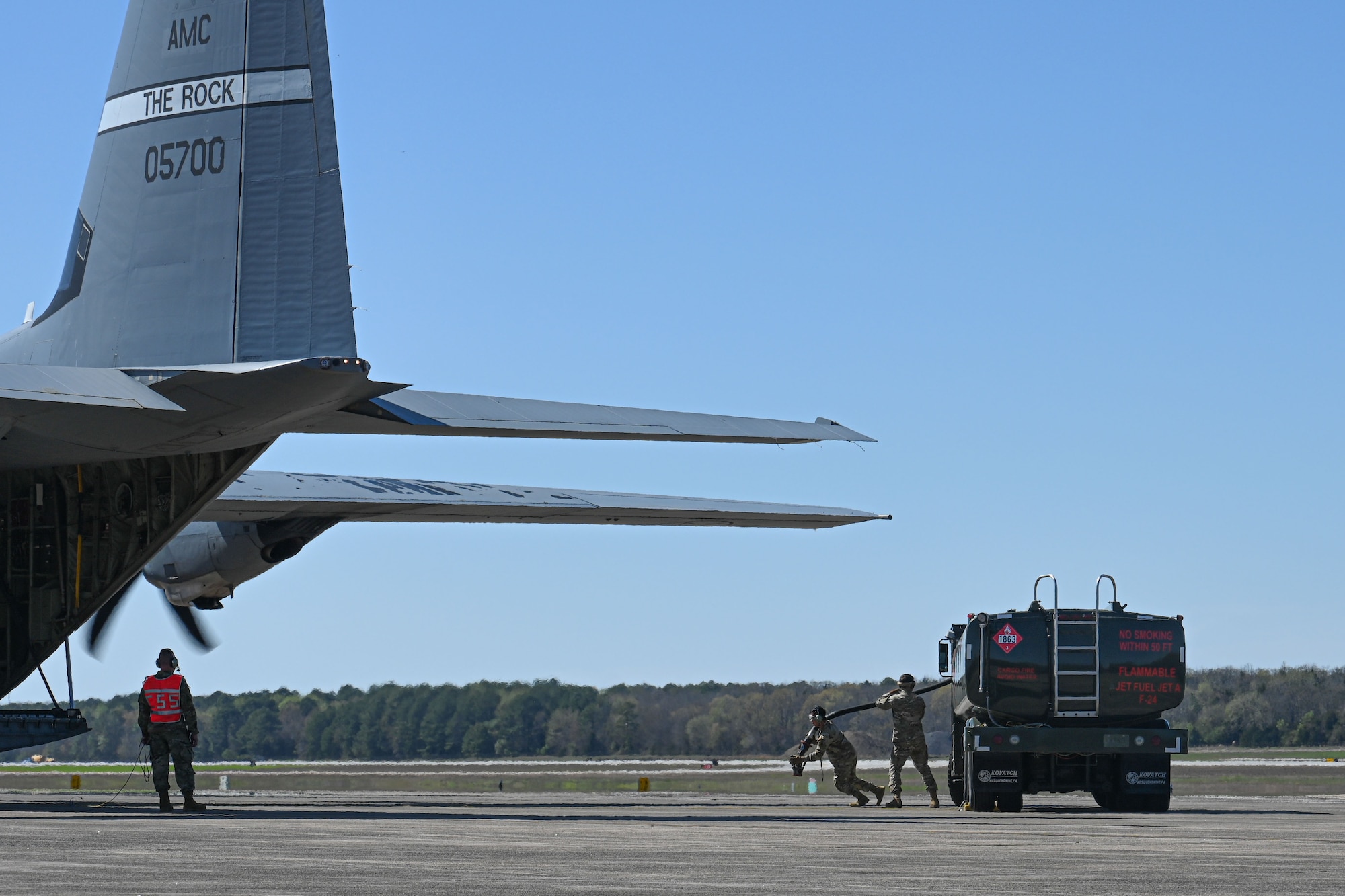 A C-130 is refueled and loaded with cargo on the flightline, while the engines run.