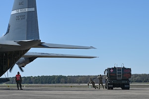 A C-130 is refueled and loaded with cargo on the flightline, while the engines run.