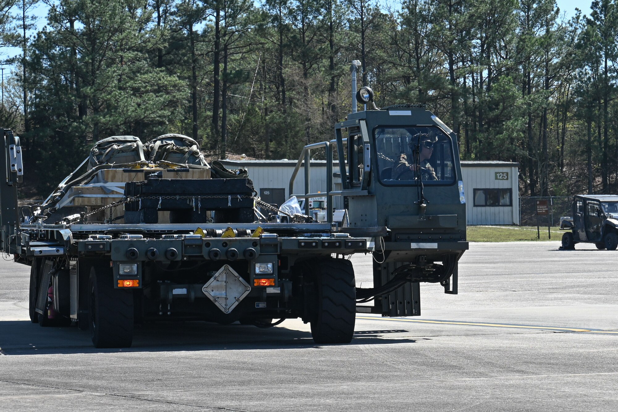 A C-130 is refueled and loaded with cargo on the flightline, while the engines run.