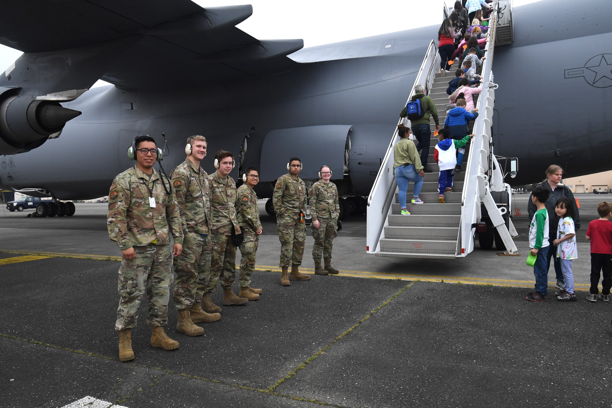A team of 730th Air Mobility Squadron passenger services and maintenance members pose for a photo during a field trip of the Yokota Passenger Terminal at Yokota Air Base, Japan, March 17, 2023. The kids filed onto a visiting Air Mobility Command C-5M Super Galaxy, which has been a feature on the Yokota flightline for a two-week ground trainer exercise hosted by the 730th AMS. The C-5M has a cargo load of 281,000 pounds and can fly 2,150 nautical miles, offload, and fly to a second base 500 nautical miles away–all without aerial refueling. With refueling, the aircraft’s range is limited only by crew endurance. (U.S. Air Force photo by Tech. Sgt. Taylor A. Workman)