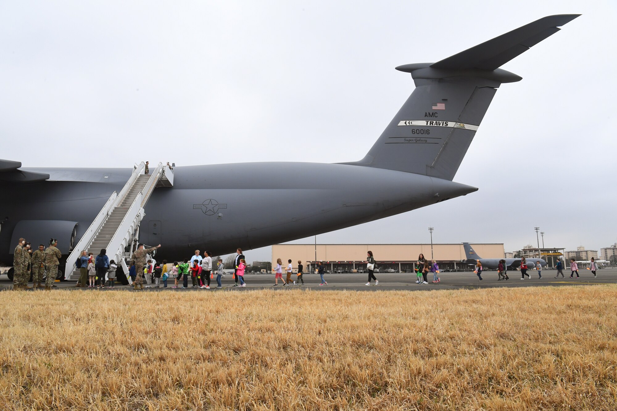 Students from Yokota West Elementary School approach a visiting Air Mobility Command C-5M Super Galaxy during a field trip of the Yokota Passenger Terminal at Yokota Air Base, Japan, March 17, 2023. The kids and their teachers marveled at the size of the air-giant, standing at a massive 20 meters tall with a wingspan of 68 meters. The C-5M has a cargo load of 281,000 pounds and can fly 2,150 nautical miles, offload, and fly to a second base 500 nautical miles away–all without aerial refueling. With refueling, the aircraft’s range is limited only by crew endurance. (U.S. Air Force photo by Tech. Sgt. Taylor A. Workman)