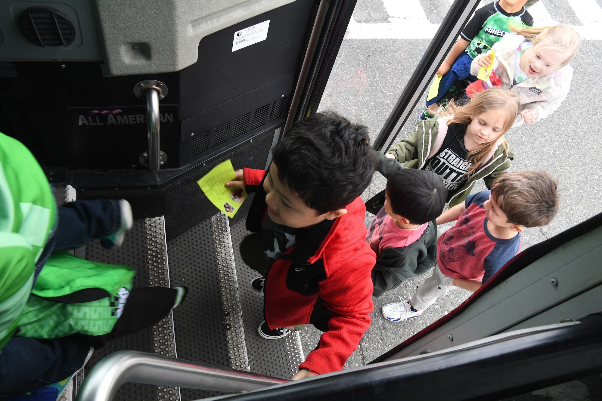 Students from Yokota West Elementary School climb into a bus during a field trip of the Yokota Passenger Terminal at Yokota Air Base, Japan, March 17, 2023. Airmen from the 374th Logistics Readiness Squadron drove the buses and escorted field trip attendees to the visiting Air Mobility Command C-5M Super Galaxy, which has been a feature on the Yokota flightline for a two-week ground trainer exercise hosted by the 730th AMS. (U.S. Air Force photo by Tech. Sgt. Taylor A. Workman)