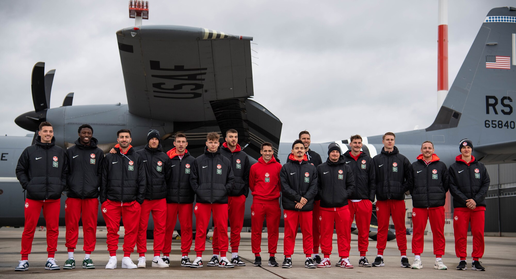 Football Club Kaiserslautern (1. FCK) players pose for a photo beside a C-130J Super Hercules aircraft assigned to the 37th Airlift Squadron at Ramstein Air Base, Germany, March 23, 2023. With 1.FCK being the largest sports team in the region, meeting with leadership and fans from RAB opens the door to future partnerships and opportunities between the team and on-base organizations. (U.S. Air Force photo by Airman 1st Class Jared Lovett)