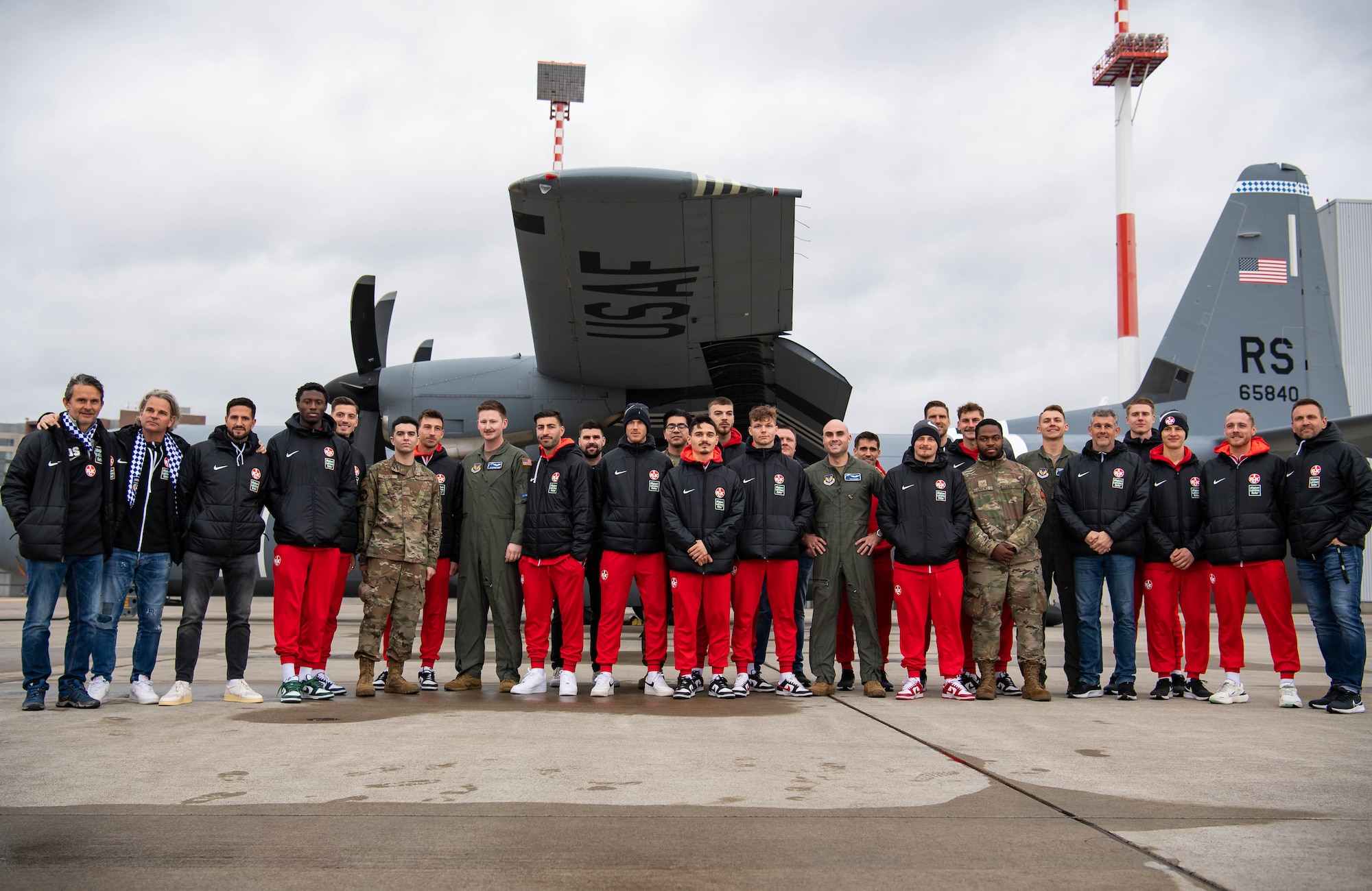 Football Club Kaiserslautern (1. FCK) players and Airmen pose for a photo beside a C-130J Super Hercules aircraft assigned to the 37th Airlift Squadron at Ramstein Air Base, Germany, March 23, 2023. The 1.FCK visit was the first time since the 1970’s that the team has visited the base and provided the players the opportunity to spend time with American fans stationed here. (U.S. Air Force photo by Airman 1st Class Jared Lovett)