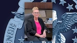 A woman poses for a photograph while sitting at her desk at work.