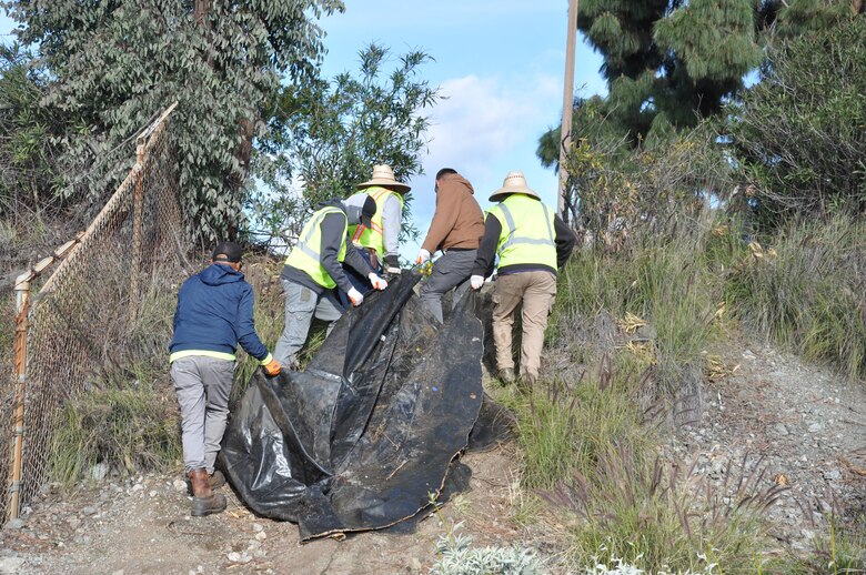 Workers drag a large waterbed up the steep embankment of the San Gabriel River, March 6, near Azuza, California.