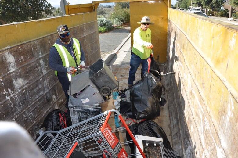 Workers drag a large black waterbed up the steep embankment of the San Gabriel River, March 6, near Azuza, California.