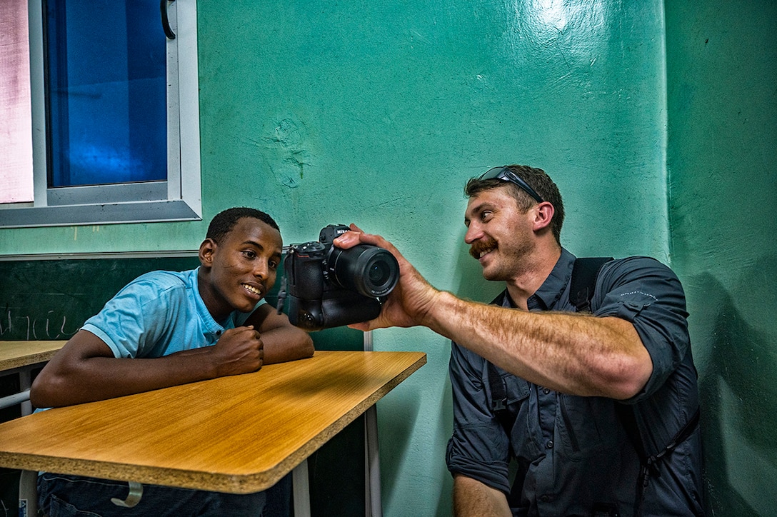 An airman shows a student the image on the viewfinder of his camera.