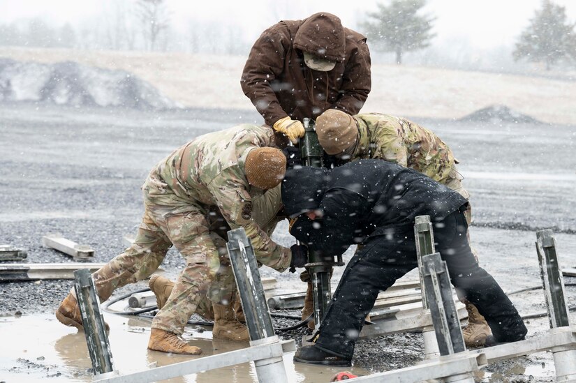 Civil engineers from 316th and 11th Civil Engineer Squadrons put stakes into the ground for the Mobile Aircraft Arresting System during a training event, March 14, 2023, Fort Indiantown Gap, Annville, Pa. Civil engineers from the 11th and 316th Civil Engineer Squadrons came together to form a team that will represent Air Force District of Washington at Readiness Challenge IX, a competition aimed to test Air Force Civil Engineers’ contingency capabilities. The MAAS is a rapidly deployed system used to stop aircraft on shorter runways or in contingency situations, and installing the system is one of the many potential competition events at the Readiness Challenge. (U.S. Air Force photo by Kristen Wong)