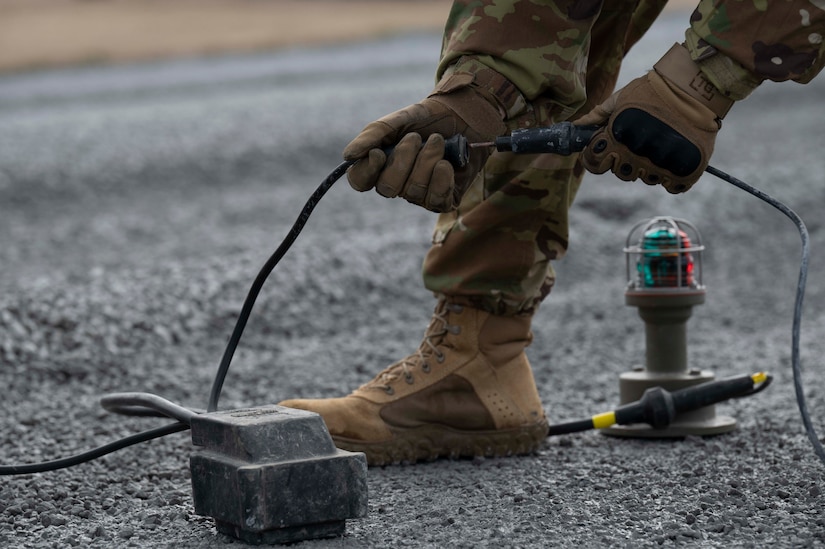 A civil engineer from 11th Civil Engineer Squadron connects lights for the Expeditionary Airfield Lighting System during a training event, March 14, 2023, Fort Indiantown Gap, Annville, Pa. Civil engineers from the 11th and 316th Civil Engineer Squadrons came together to form a team that will represent Air Force District of Washington at Readiness Challenge IX, a competition aimed to test Air Force Civil Engineers’ contingency capabilities. The EALS is a rapidly installed runway lighting system that supports flying operations during periods of reduced visibility on contingency airfields, and the installation of the system is one of the many potential competition events at the Readiness Challenge. (U.S. Air Force photo by Kristen Wong)