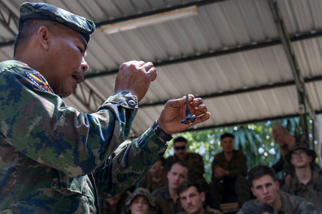 A Marine holds a scorpion in his hand.