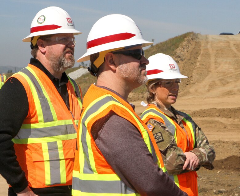 Col. Julie Balten, LA District commander, right, joins Derek Walker, project manager with the LA District, left, and Travis Tutka, acting Dam and Levee Branch chief for the Corps’ headquarters in Washington D.C., center, to watch the emplacement of a 19-ton floodgate March 10 on the Alcoa Dike alongside the Temescal Wash in Corona, California.