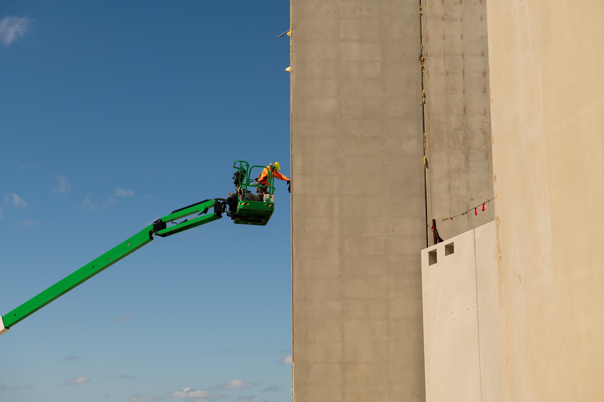 A construction worker stands in a cherry picker