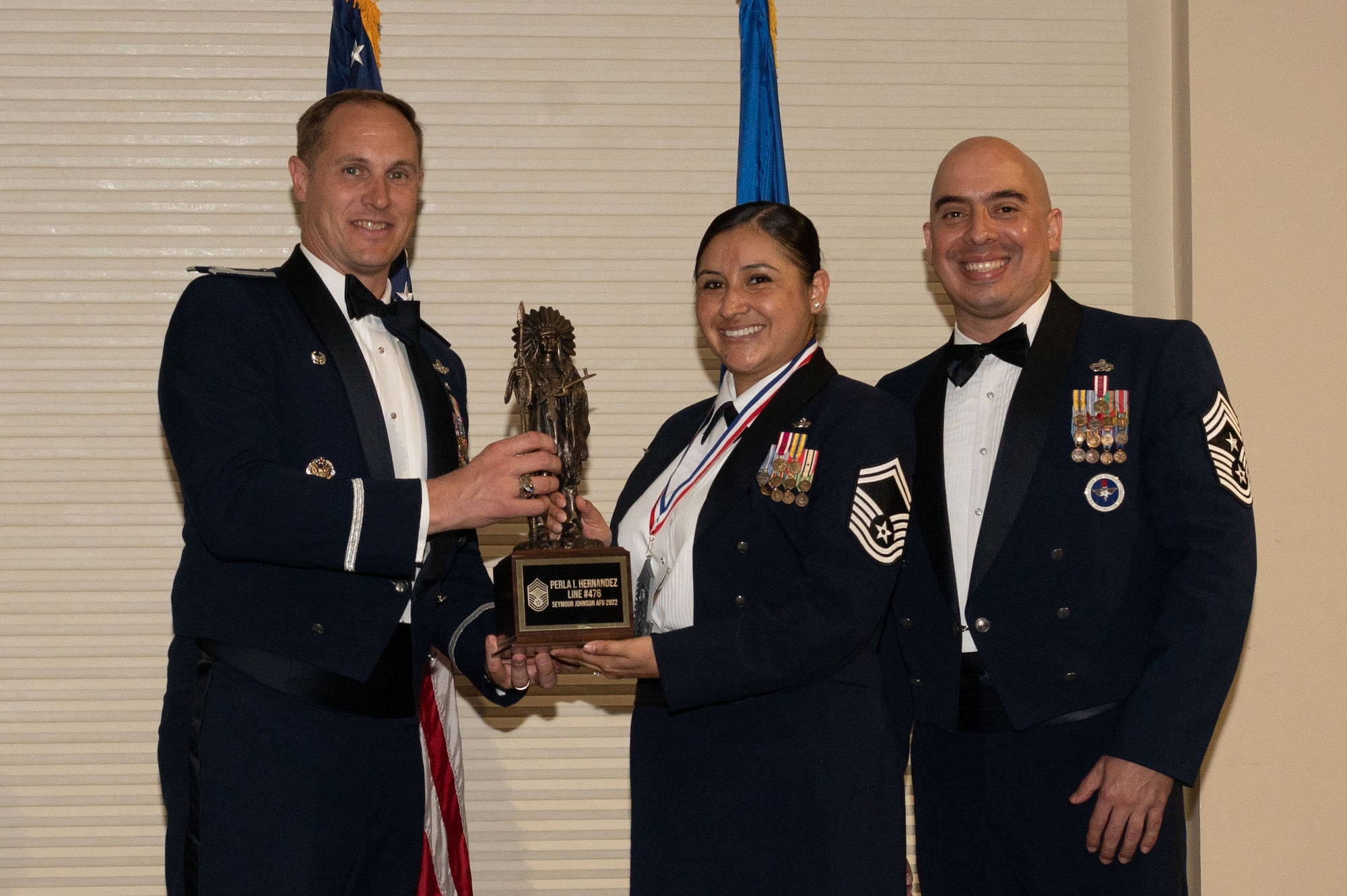 Col. Lucas Teel, 4th Fighter Wing commander, and Chief Master Sgt. Peter Martinez, 4th FW command chief, present a trophy to Senior Master Sgt. Perla Hernandez, 4th Force Support Squadron sustainment services flight chief, during a Chief Master Sergeant Recognition Ceremony at Seymour Johnson Air Force Base, North Carolina, March 24, 2023. Chief master sergeant is the ninth and highest enlisted rank in the U.S. Air Force. (U.S. Air Force photo by Airman 1st Class Rebecca Sirimarco-Lang)