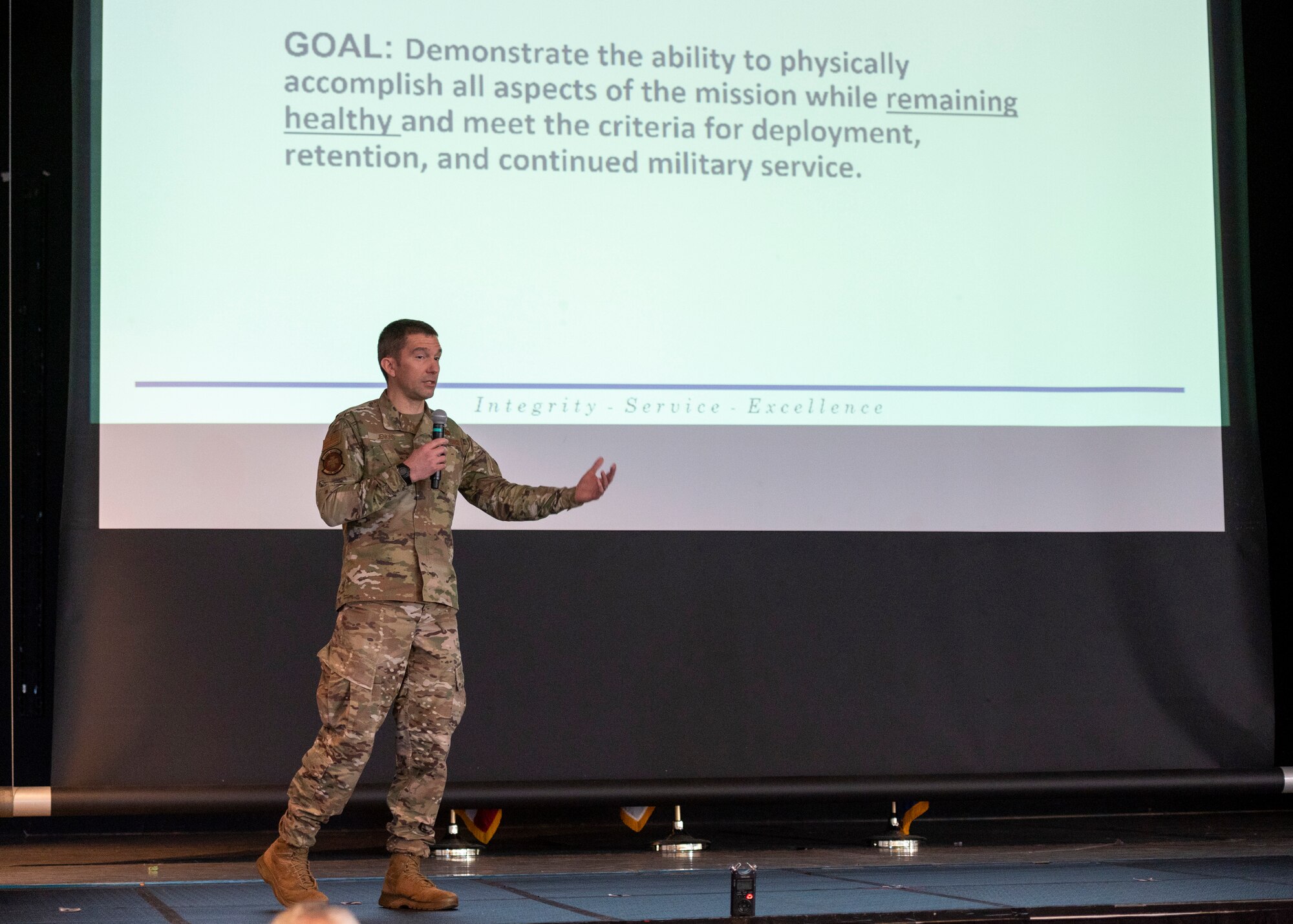 A military doctor gives a presentation on stage