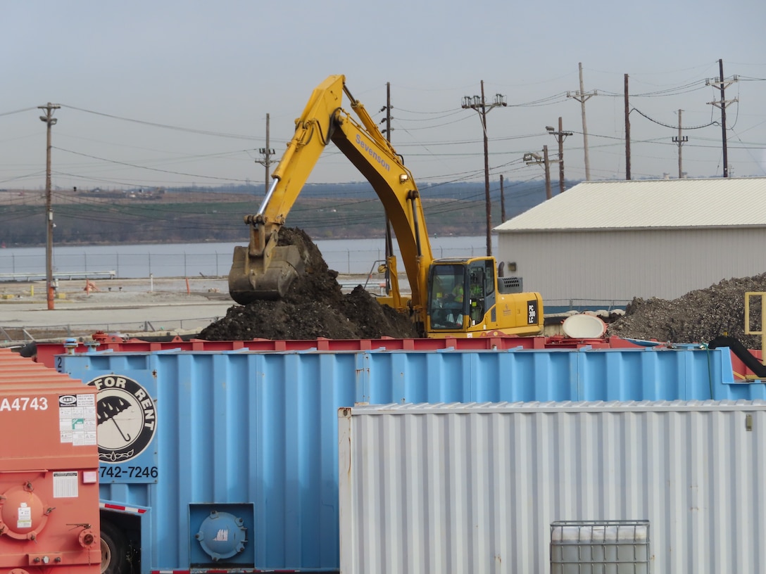 Excavator removes contaminated soil from a site