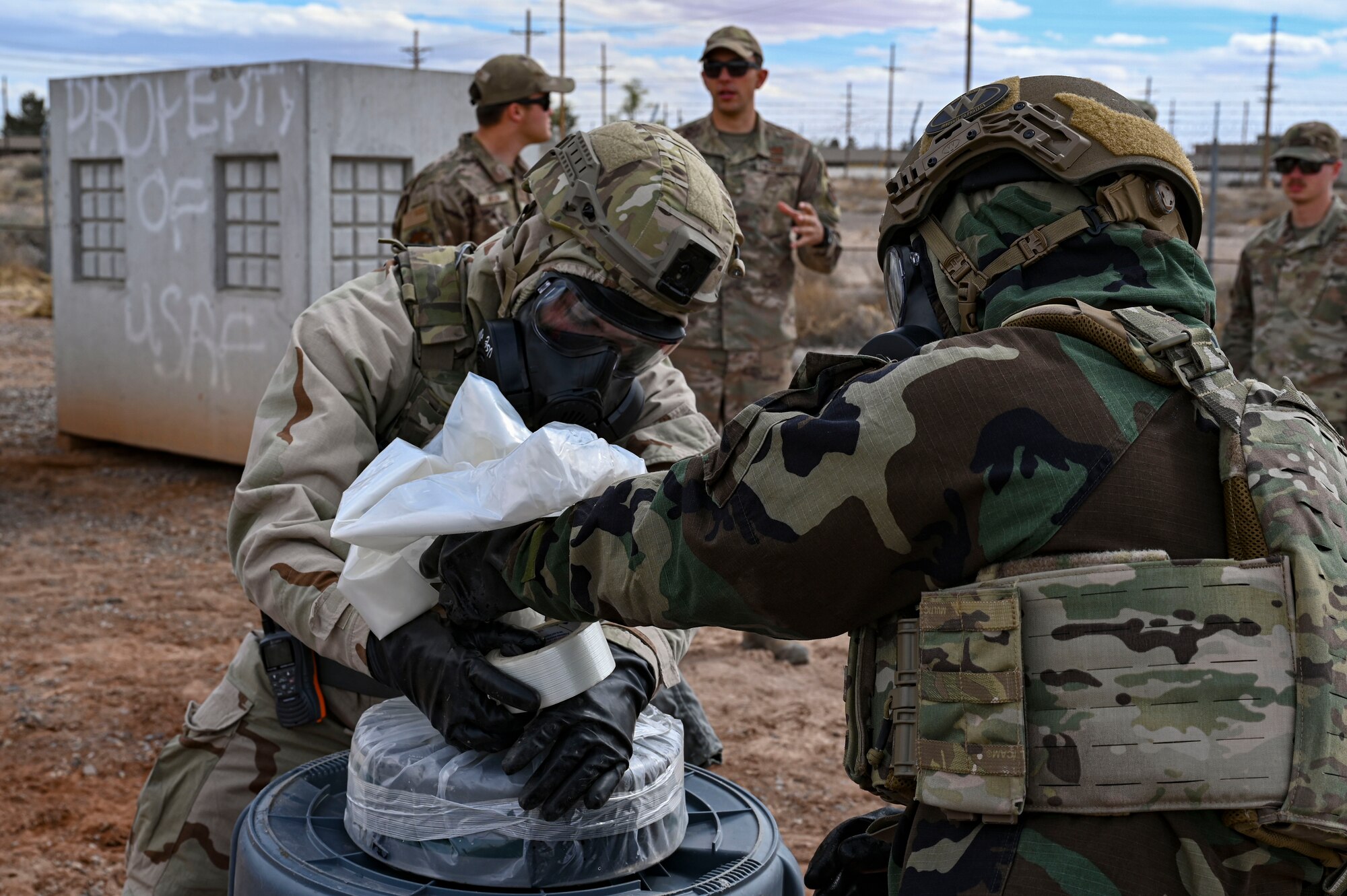 U.S. Air Force Airman 1st Class Spencer Pettingill, left, and U.S. Air Force Senior Airman Danielle Alpi, 49th Civil Engineer Squadron explosive ordnance disposal apprentices, wrap up an M23 chemical landmine during a chemical munition decontamination exercise at Holloman Air Force Base, New Mexico, March 23, 2023. The 49th CES EOD flight works meticulously to provide maximum safety when it comes to dealing with chemical contaminations, ensuring that any volatile materials are properly contained. (U.S Air Force photo by Airman 1st Class Isaiah Pedrazzini)