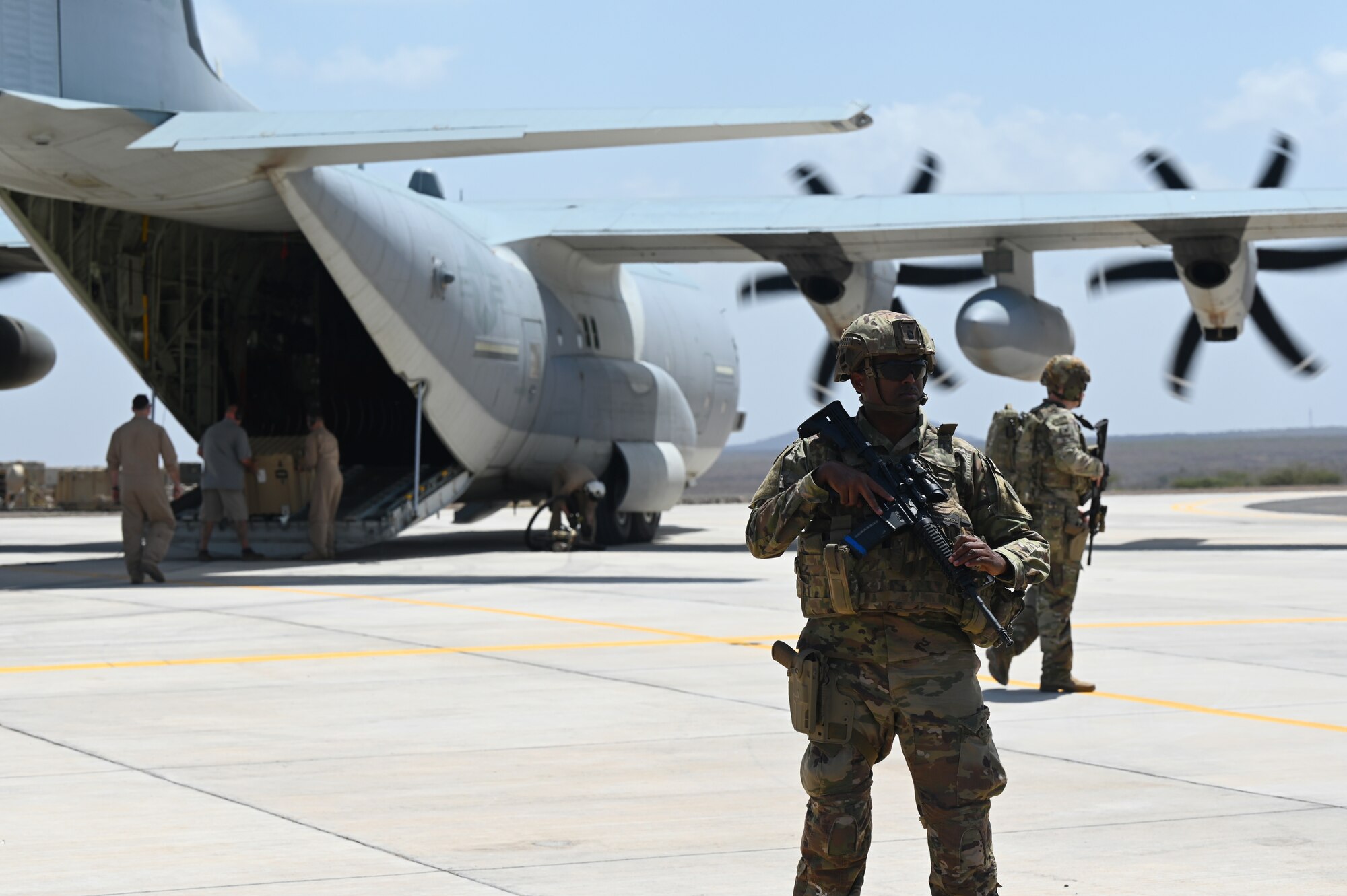 U.S. Army security personnel organize a perimeter around a KC-130 as its U.S. Marine Corps crew members unload supplies in support of a simulated Forward Arming and Refueling Point (FARP) exercise at Chabelley Airfield, Djibouti, Feb. 22, 2023. The ability of a Joint Force Commander to move their forces fluidly across the theater to seize, retain and utilize initiatives against an adversary is key to ensuring readiness and resilience, and protecting assets and personnel. (U.S. Air Force photo by Tech. Sgt. Jayson Burns)