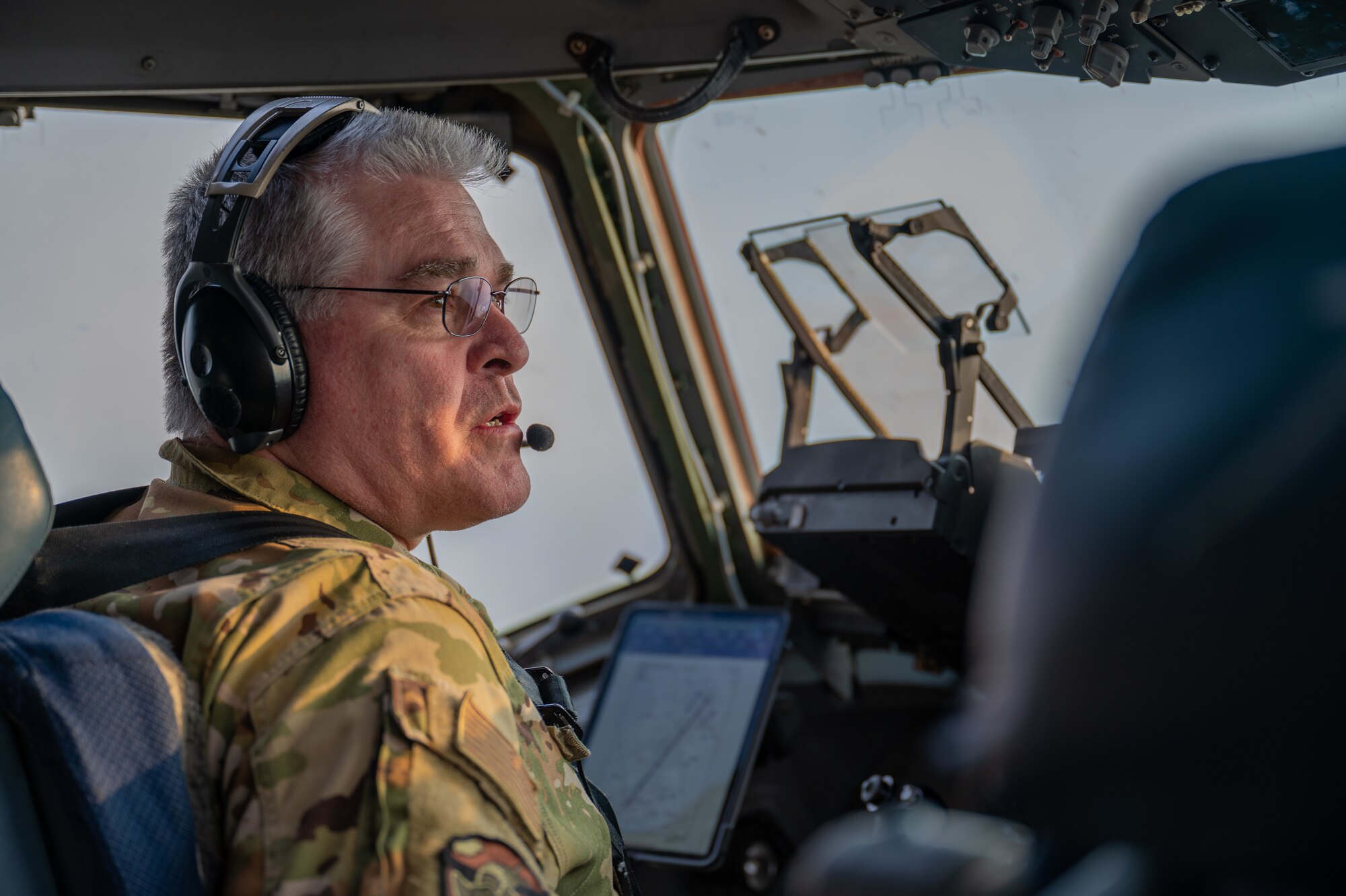 Col Mark Hahn sits in the cockpit of a C17 Globemaster as he flies and speaks into his headset.