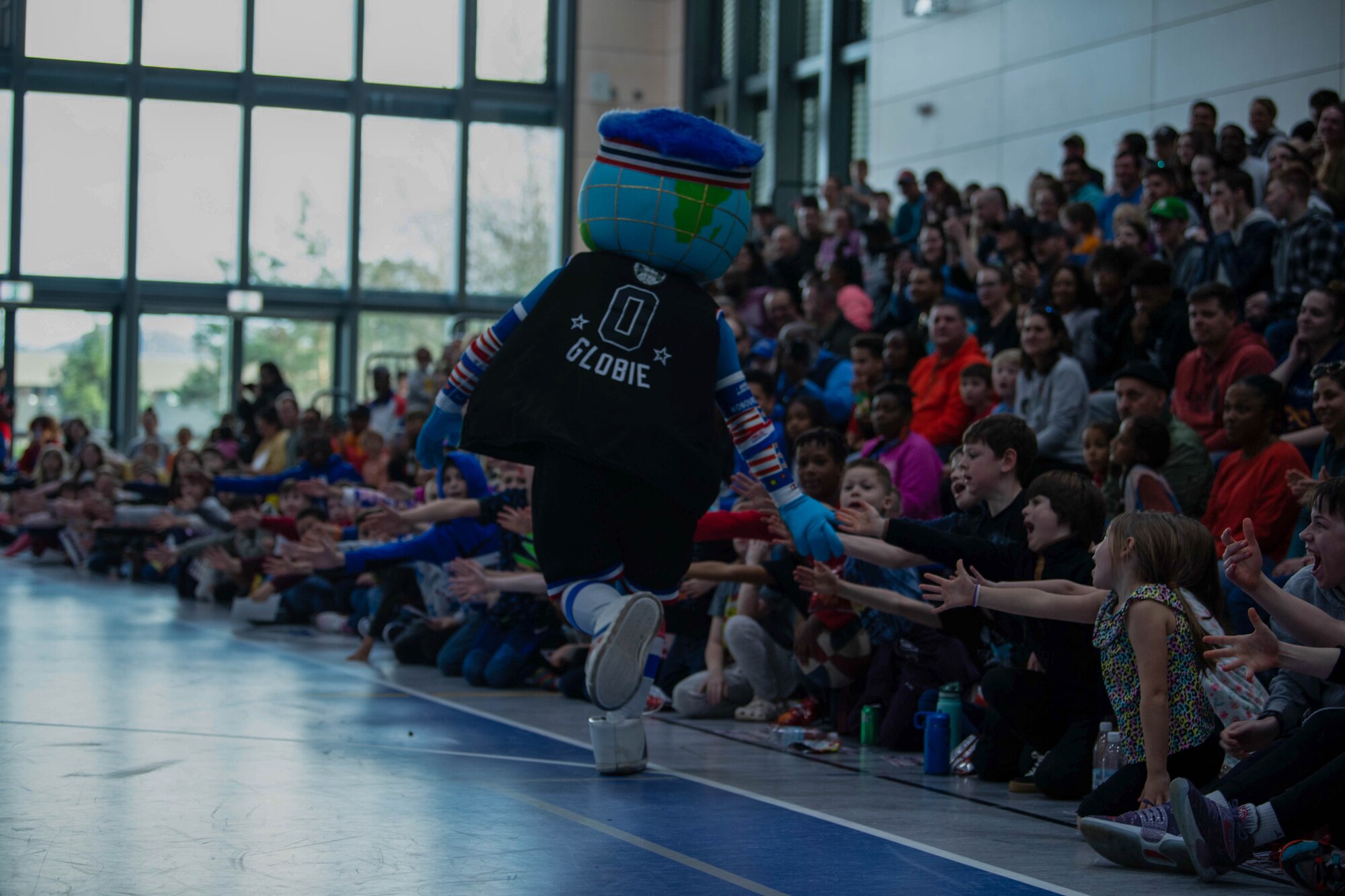 Globe, the Harlem Globetrotters mascot, high-fives children in a crowd at Ramstein Air Base, Germany, March 24, 2023.