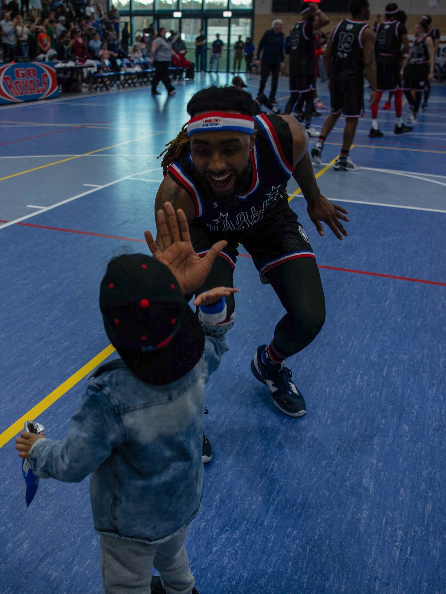 A Harlem Globetrotters player gives a child from the audience a high-five at Ramstein Air Base, Germany,  March 24, 2023.