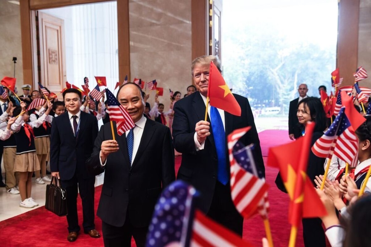 US President Donald Trump (R) holds a Vietnamese flag as Vietnam's Prime Minister Nguyen Xuan Phuc (C) holds a US flag upon their arrival for a meeting at the Government Office in Hanoi on February 27, 2019, ahead of the second US-North Korea summit. (Photo by Saul LOEB / AFP) (Photo by SAUL LOEB/AFP via Getty Images)