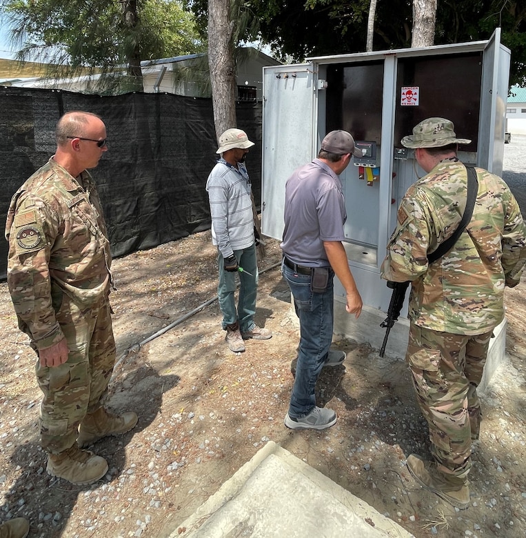 A contractor shows a group of personnel from the 475th Expeditionary Air Base Squadron base civil engineer team one of the transfer switches at Camp Simba, Kenya, that needs to be rewired. The 405th Army Field Support Brigade’s Logistics Civil Augmentation Program is working a letter of technical direction in order to conduct a project to access the feeder pillars and the distribution lines and cables that run throughout the east side of the camp. (U.S. Army courtesy photo)