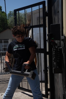 Delegate swings a battering ram breaching tool into a training door during a SWAT demonstration