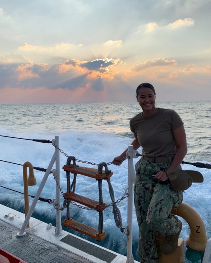 Then Petty Officer First Class Sharina Komen stands on the deck of the Coast Guard Cutter Maui while underway in 2020.