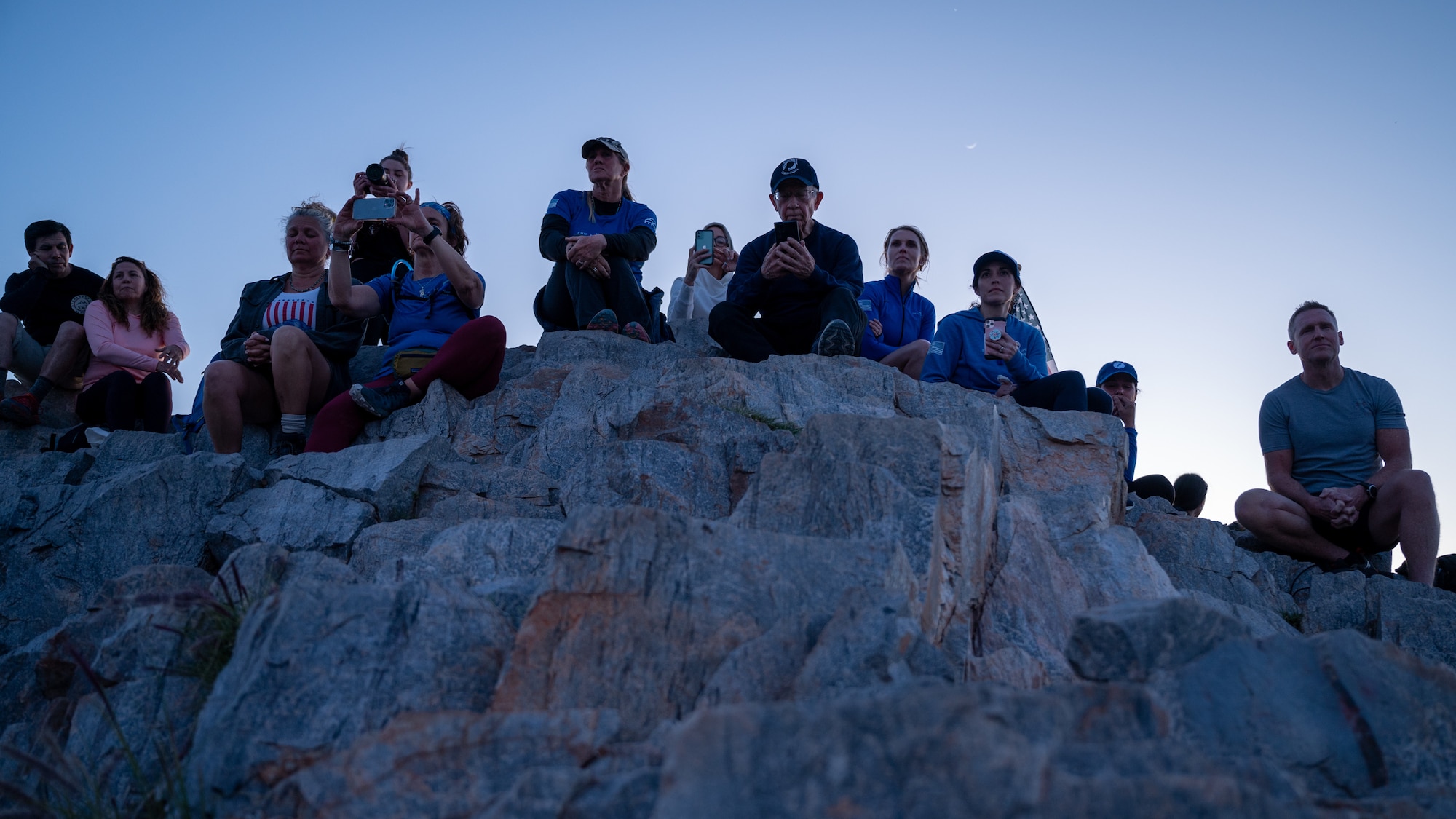 Participants of the Wear Blue: Run to Remember Piestewa Challenge sit at the top of Piestewa Peak March 26, 2023, in Phoenix, Arizona.
