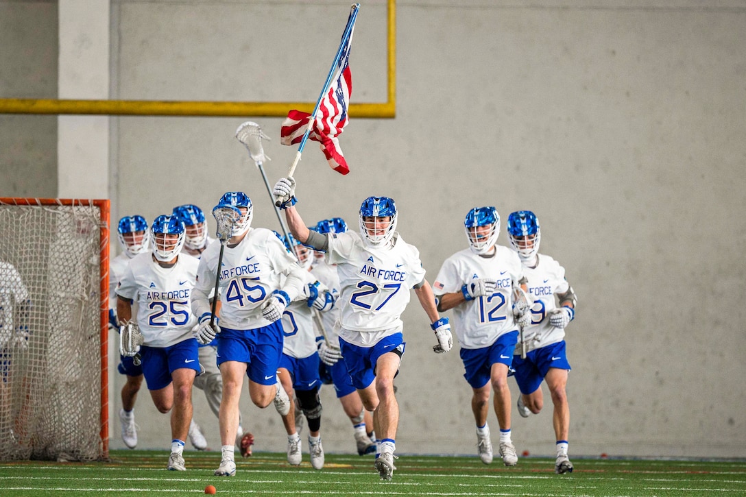 U.S. Air Force Academy lacrosse players run onto a field.