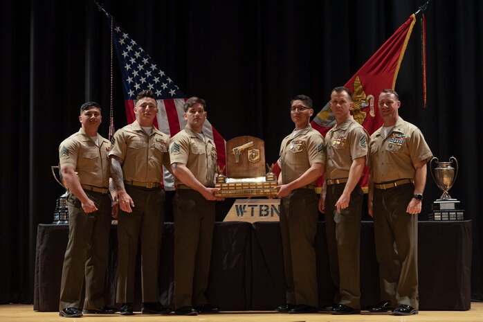 U.S. Marines pose for a photo with the 2023 Marine Corps Marksmanship Competition East pistol match trophy at the Base Theater on Marine Corps Base Camp Lejeune, North Carolina, March 17, 2023.  The winners of this year’s pistol match were Marine Corps Security Forces Training Company Team 1.