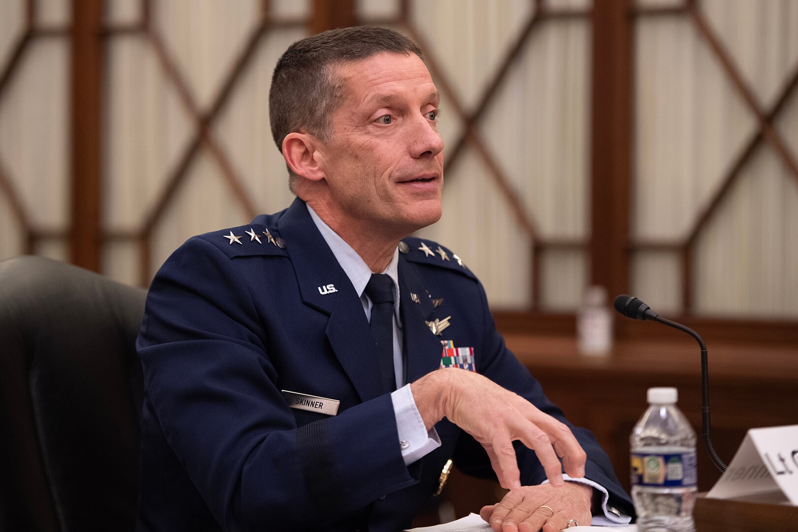 A man in a military uniform sits in front of a microphone.