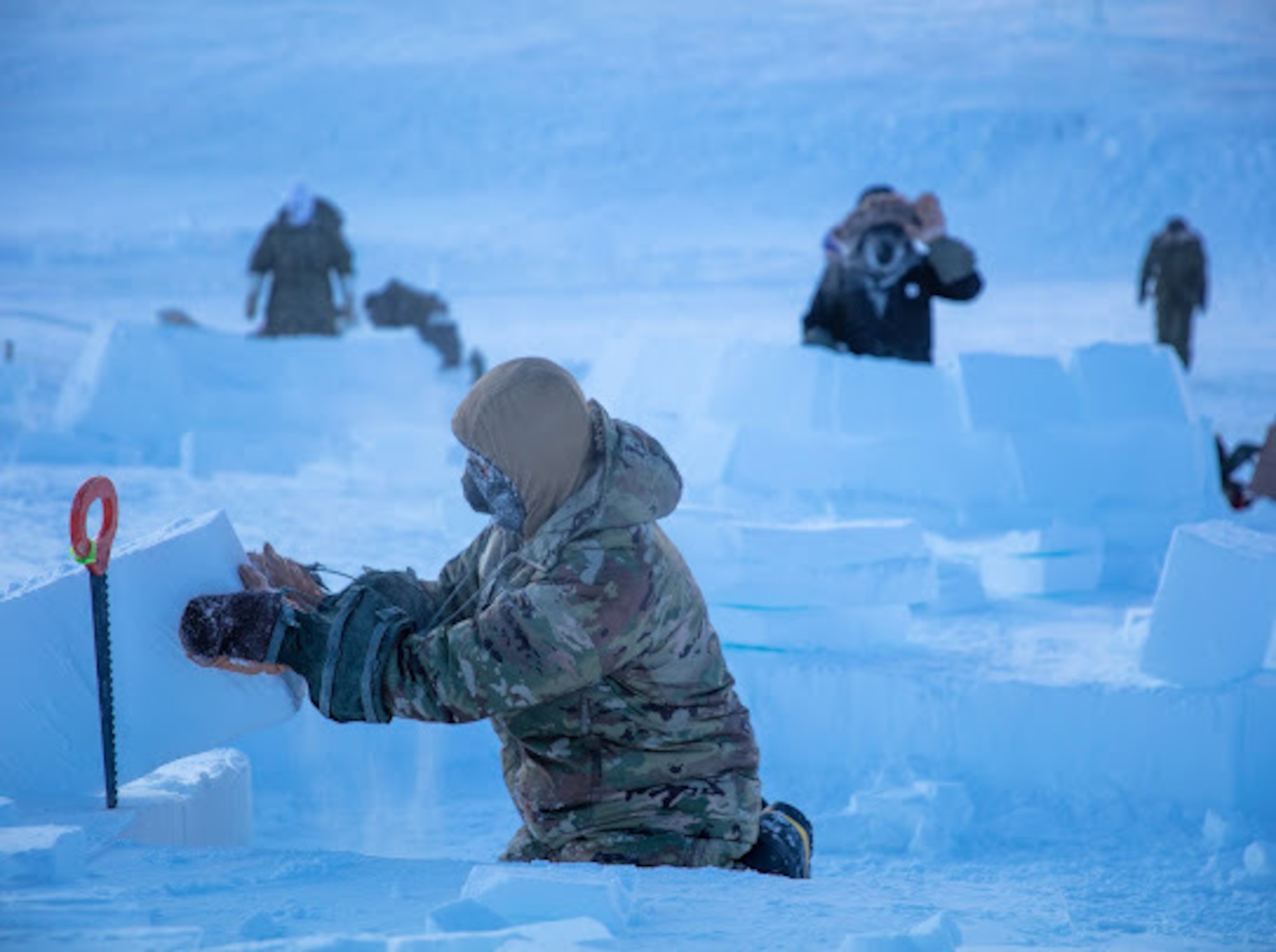 U.S. Air Force Chief Master Sgt. Jeremiah Wickenhauser cuts snow blocks to be used in igloo constriction in Crystal City, Canada.