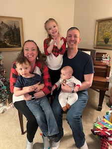 A man and woman poses for photo with three children.