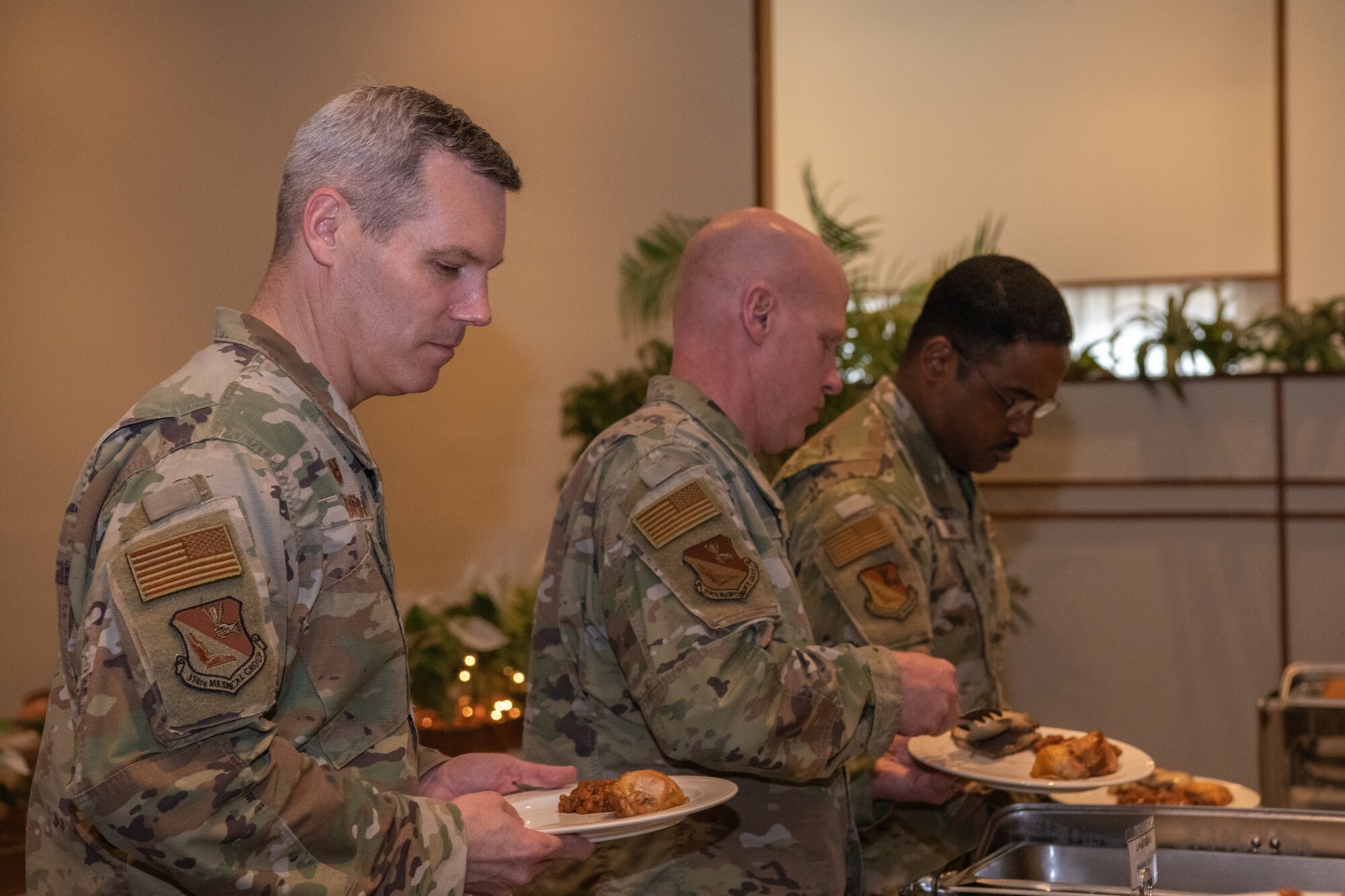 Men filling plates at a buffet.