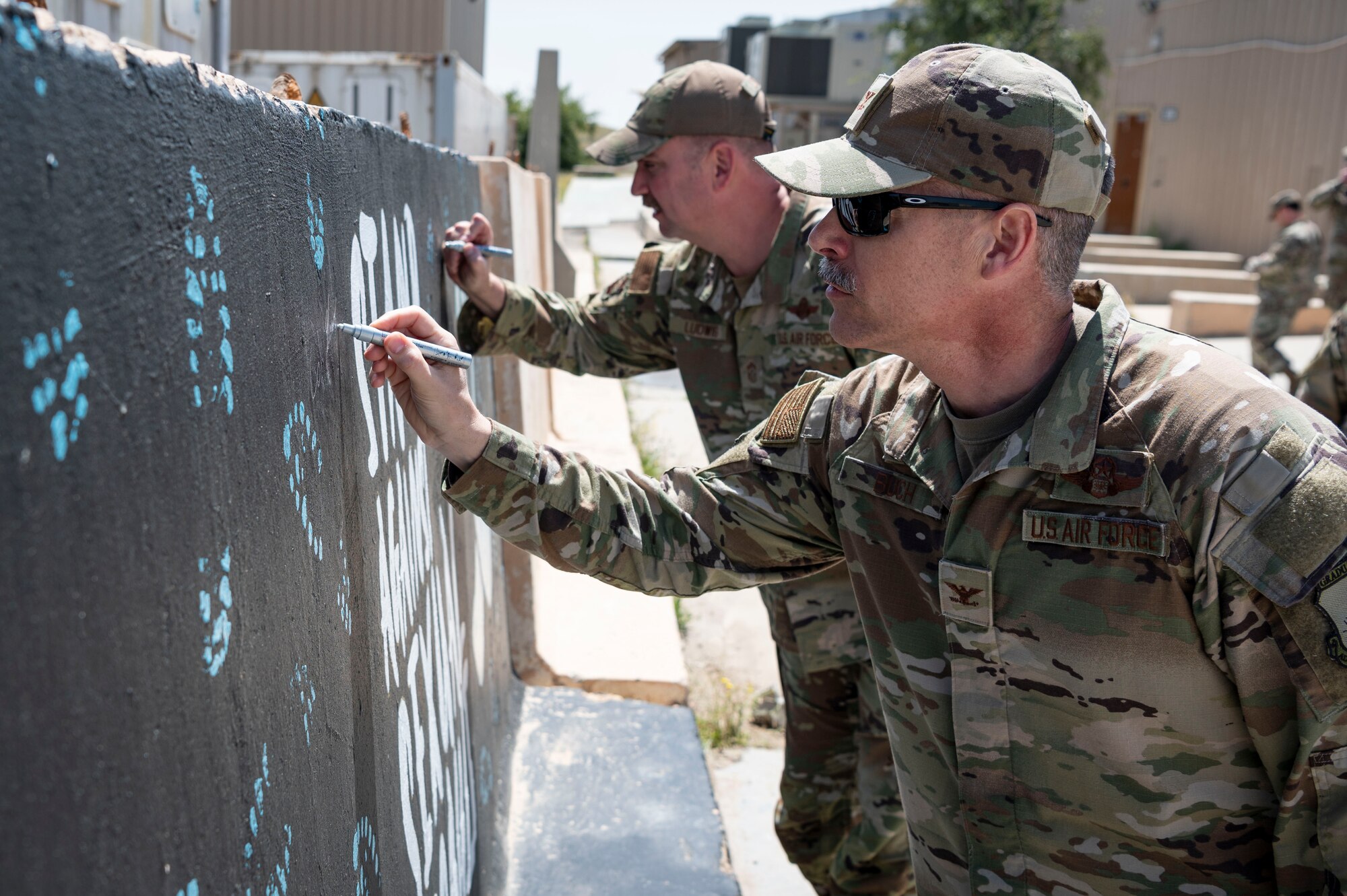 U.S. Air Force Col. George Buch, 386th Air Expeditionary Wing commander, and Chief Master Sgt. Louis Ludwig, 386th AEW command chief, sign a mural to signify April 1st as the start of Sexual Assault Awareness and Prevention month at Ali Al Salem Air Base, Kuwait, March 27, 2023.