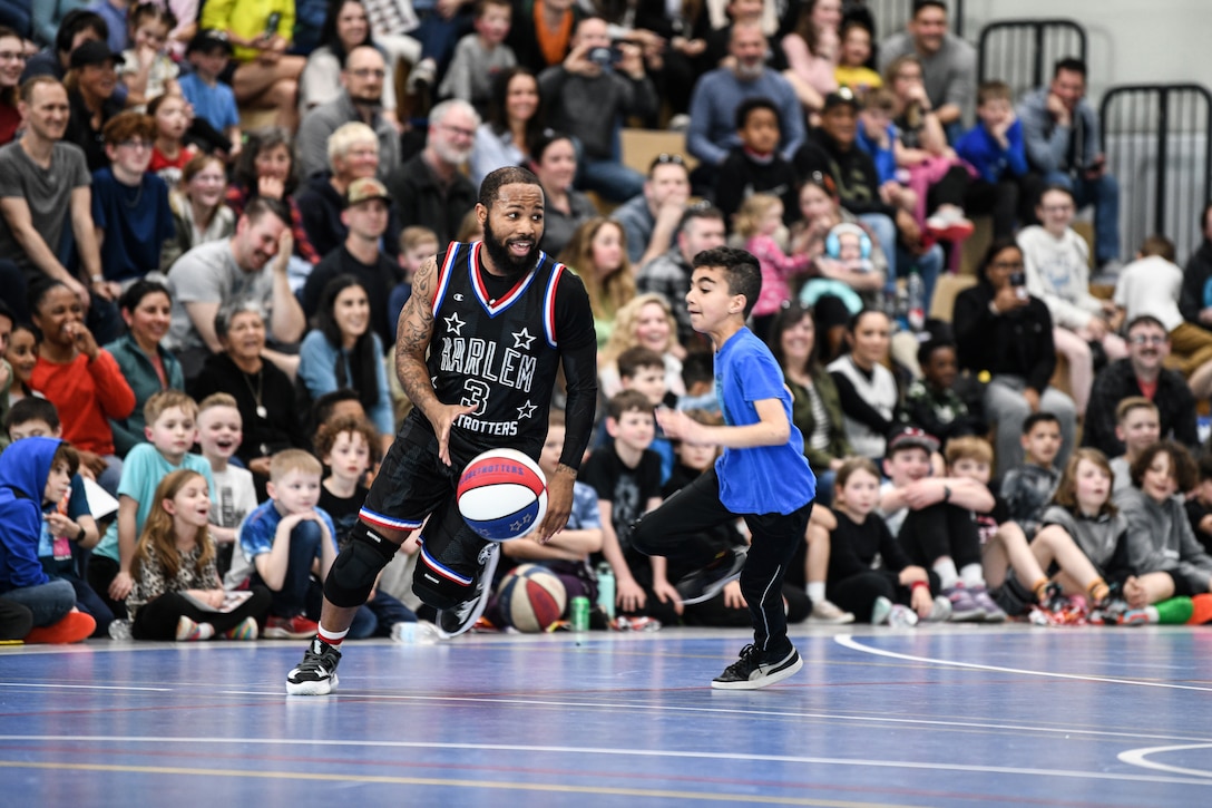 A young boy tries to guard a basketball player.