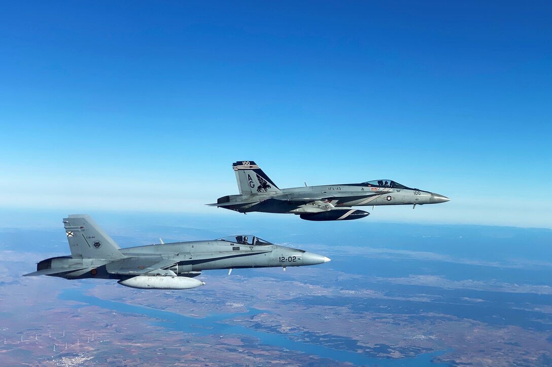 Two military jets fly through the sky.