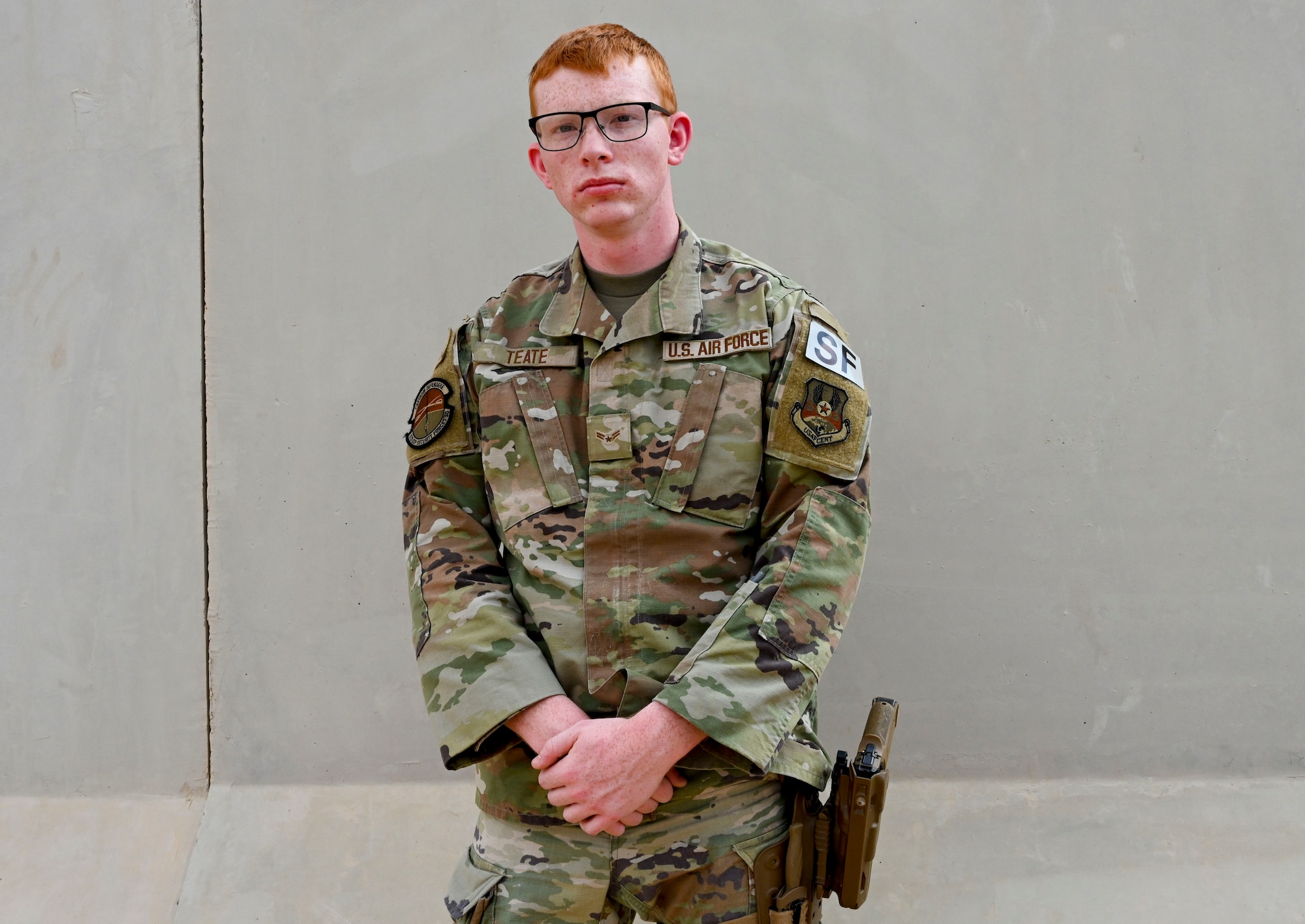 U.S. Airman 1st Class Cameron Teate, 378th Expeditionary Security Forces counter small unmanned aircraft systems operator, stands in front of a T-Wall at Prince Sultan Air Base, Saudi Arabia, March 15, 2023. Teate has spent more time deployed than at his first duty station and currently operates a variety of systems with detect and defeat capabilities. (U.S. Air photo by Senior Airman Joao Marcus Costa)