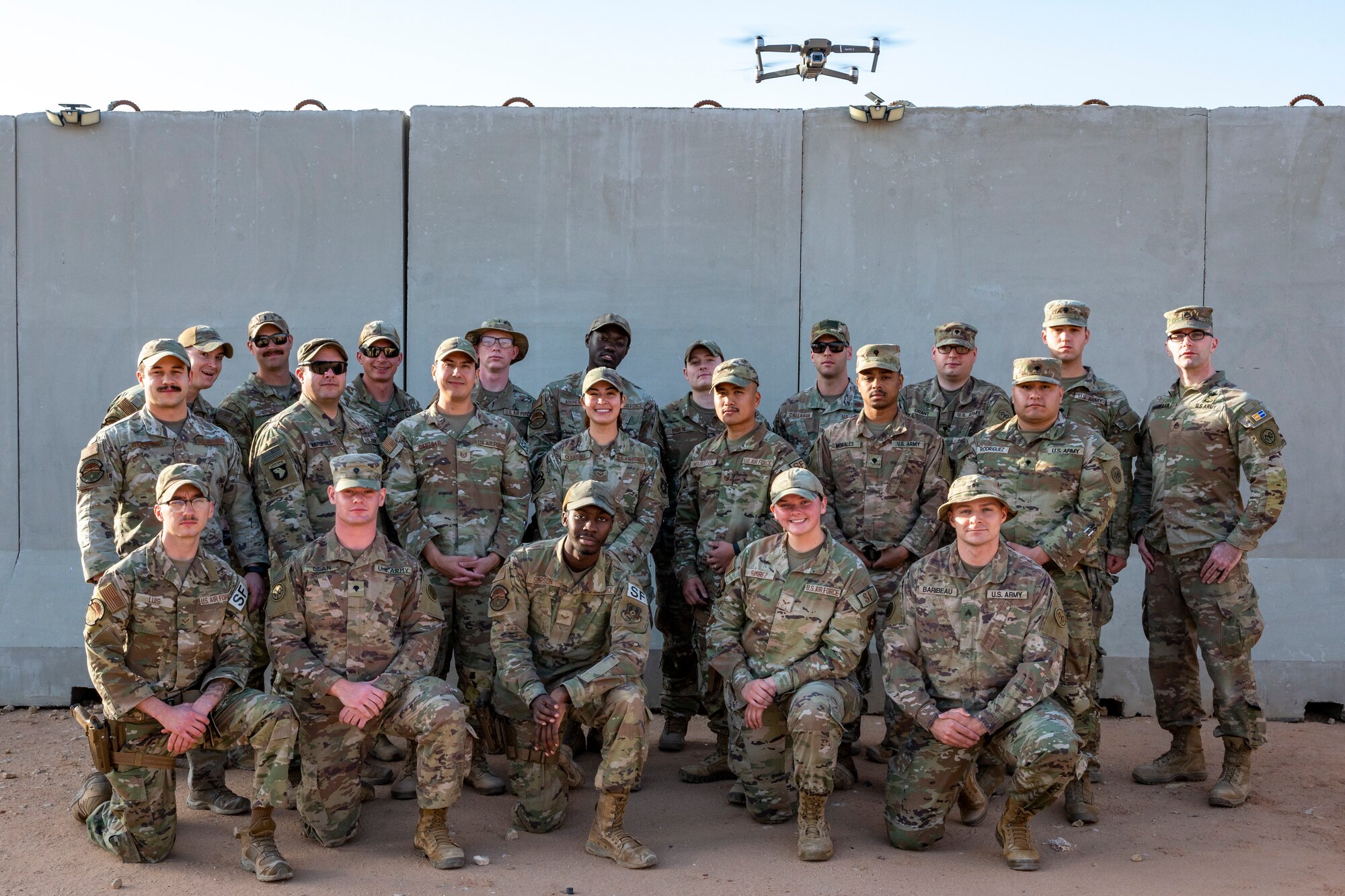 U.S. service members assigned to the Base Air Defense Center stand in front of a T-Wall at Prince Sultan Air Base, Saudi Arabia, Feb. 25, 2023. The team had huge successes during their deployment cycle, to include having their Tactics, Technics, and Procedures become the standard for the U.S. Central Command Area of Responsibility. (U.S. Air photo by Senior Airman Stephani Barge)