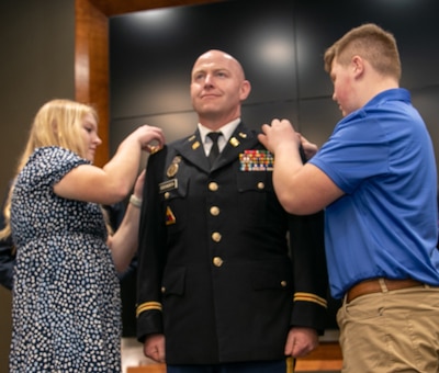 Norah and Liam Dodsworth, the children of newly promoted Lt. Col. Matthew Dodsworth, affixes new rank on his uniform during a promotion ceremony March 3 at the Illinois Military Academy on Camp Lincoln, Springfield, Illinois.