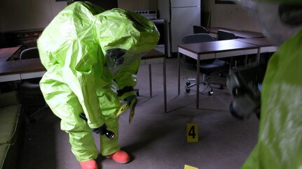 Army CID agent in biohazard protective equipment collects evidence at the scene of a crime