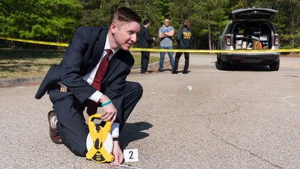 Army CID agent collects evidence at a crime scene outside