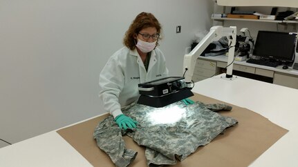 Army CID forensic scientist collects evidence from clothing in lab