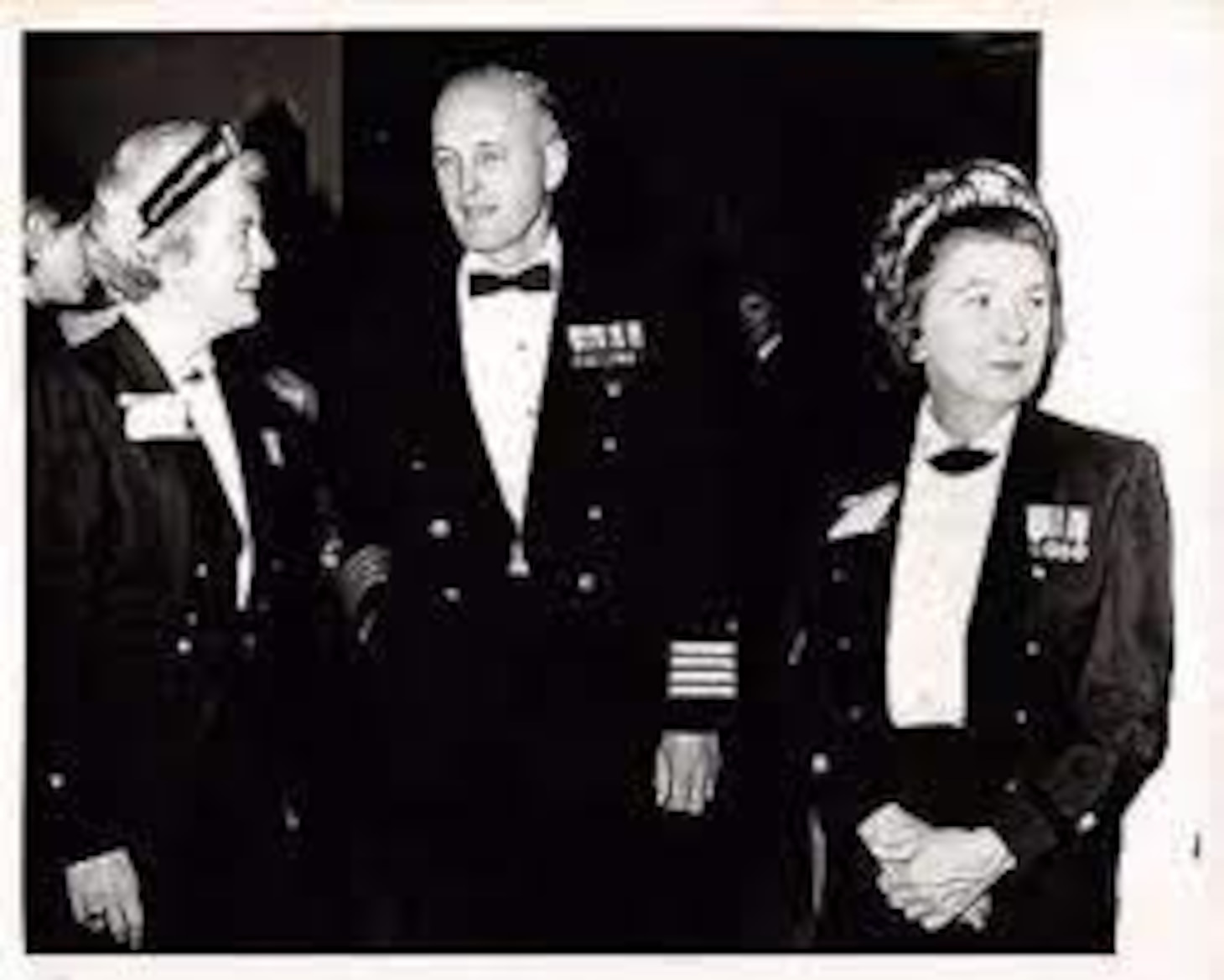 Black and white photo of sailors in uniform chatting, Alma Ellis on the right