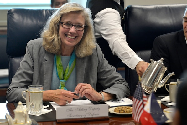 Smiling woman in grey blazer and green scarf sitting at the table