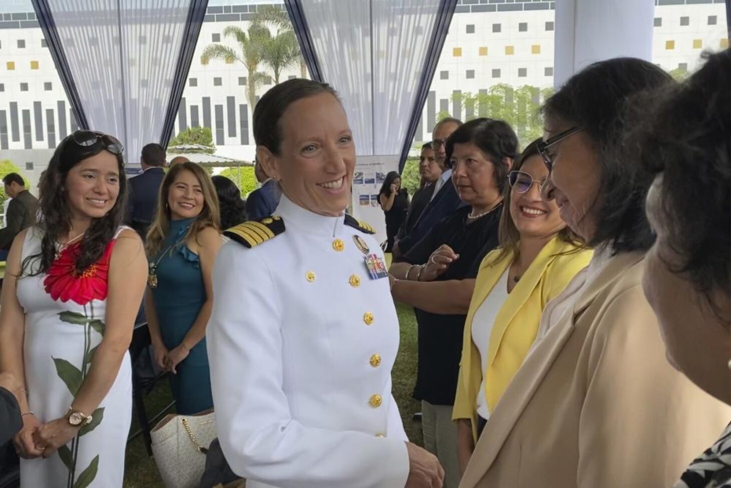 Smiling woman in white uniform chatting with women at ceremony